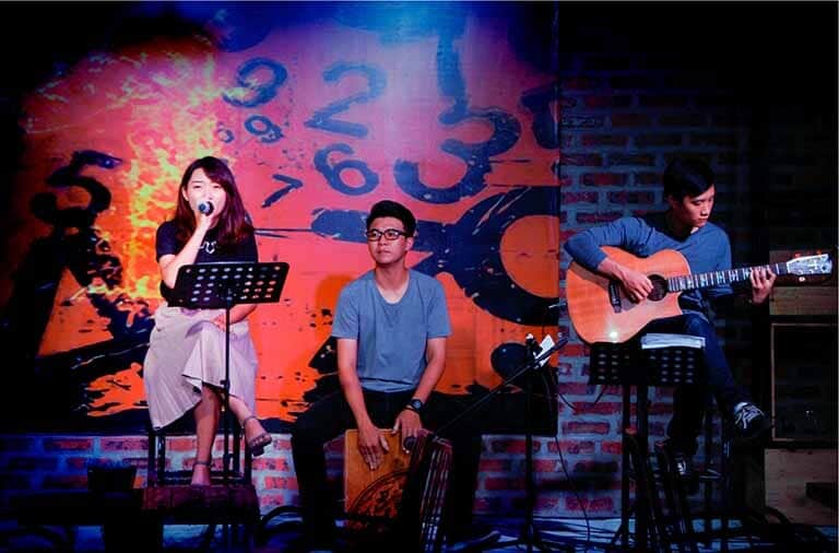 Hình ảnh một ca sĩ đang hát trong phòng trà, có micro thu âm